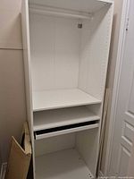 Front view of white PAX wardrobe showing hanging rod, shelf, felt drawer