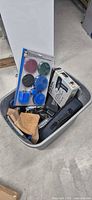 Grey tote containing assorted tools including heat gun box, drill brush set, tool case and leather pouch