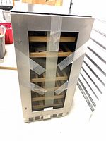 Front view of stainless steel wine cooler with glass door and shelves visible