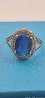 Front view of ring showing oval blue stone, halo and split shank
