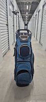 Front view of blue cart golf bag standing upright in storage corridor