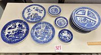 Assorted Blue Willow style plates laid out showing sizes and patterns