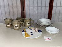 Group shot: four Sonoma mugs, four plates, four Corelle bowls, snowman plate