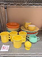 Shelf with stacked dinner plates, bowls, mugs, creamer, sugar bowl and salt shaker