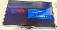 Front view of TV powered on showing "No Signal" message