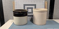 Both stoneware crocks side by side with measuring grid for scale