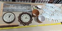 Overall lot layout showing sign, two clocks, pots, bowls, hook, stake, metal pigs