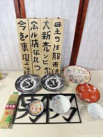 Group shot of entire lot showing plates, bowls, wooden panels, metal trivets and sushi mat