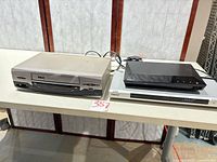 Three playback units on table: RCA VCR, Sony DVD player, Sony Blu-ray player stacked