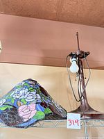 Leaded glass floral shade alongside metal lamp base