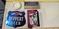 Overview of all four items: Ruppert sign, Ballantine sign, Coors ashtray, boxed corkscrew