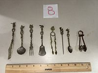 All eight utensils lined by ruler for scale