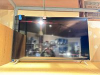 Front view of Vizio 60-inch TV on shelf with stand legs attached