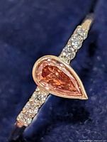 Front view of ring showing pear-cut pink center stone and accent diamonds