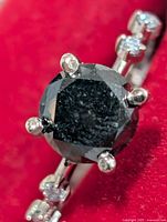 Close-up of round black diamond centre stone in prong setting