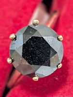 Front view of black diamond ring showing stone and prongs