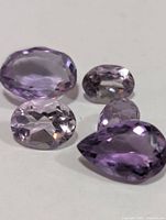 Four loose faceted amethyst stones on white background