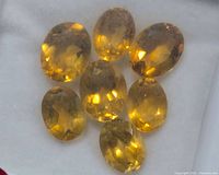 Seven oval citrine gemstones on white background