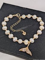 Bracelet laid flat showing pearls, spacers, whale tail charm