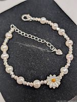 Full view of pearl bracelet showing pearls, spacers, clasp, extender, daisy charm