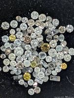 Close-up of assorted loose diamonds on black background showing variety of sizes and colors