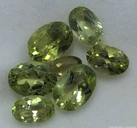 Eight oval-cut peridots loose on pad