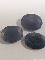 Three oval faceted blue sapphires on white background