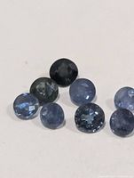 Group of eight round blue sapphires on white background