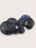 Six faceted sapphire gemstones grouped on white background