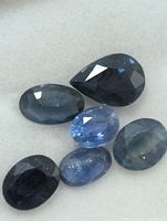 Six loose blue sapphires on white background, showing color and cuts