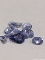 Eight loose violet-blue faceted tanzanite stones on white background