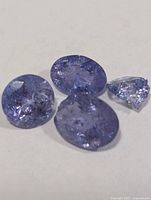 Four loose tanzanite stones on a white background