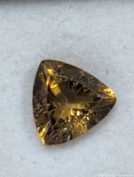 Close-up of faceted golden-brown triangular tourmaline on white pad