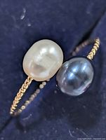 Close-up of white and peacock pearls on ring