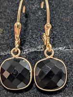 Front view of earrings showing black onyx stones and yellow-tone bezel settings