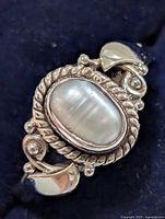 Top view showing oval mother-of-pearl cabochon and decorative silver scrollwork