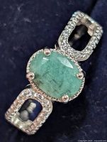 Close-up of emerald center stone and CZ halo