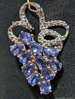 Front view of silver pendant with cluster of tanzanites and ribbon detail