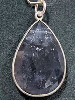 Front view of teardrop faceted iolite pendant in silver bezel