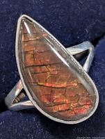 Front view of pear-shaped ammolite ring in silver bezel setting