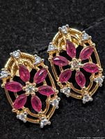 Front view of both earrings displaying rubies and clear accent stones