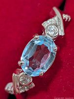 Top view of silver ring showing oval blue topaz and side accents