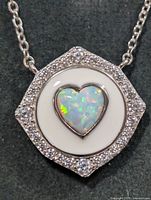 Close-up of pendant front showing opal heart, enamel disc, CZ halo
