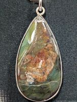 Front view of teardrop rhyolite pendant in silver bezel