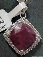 Front view of sterling silver pendant highlighting cushion-cut red centre stone and halo setting