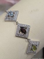 Close-up of bracelet square link showing blue topaz and pavé border