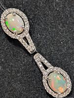 full view of one drop earring showing two opals with CZ halos