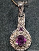 Front view of silver pendant showing round amethyst, diamond-shaped amethyst accent and CZ accents