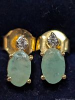 Front view of the pair of emerald stud earrings showing stones and accent stones