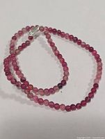 Full view of pink tourmaline bead necklace coiled showing beads and clasp